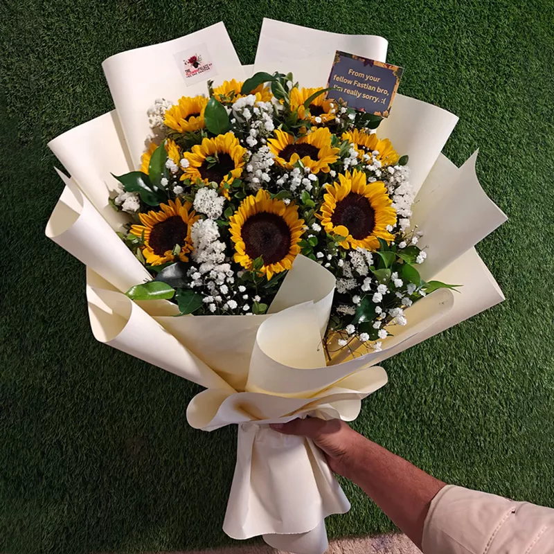 Large bouquet of vibrant sunflowers and white fillers wrapped in premium cream/white paper