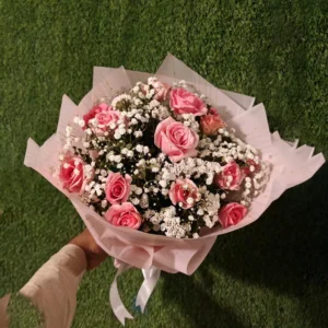 Pink roses bouquet heavily layered with white Gypsophila (baby's breath) in soft pink wrapping
