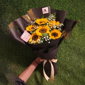 Sunflowers with butterfly accents and light gold ribbon in a black paper wrap