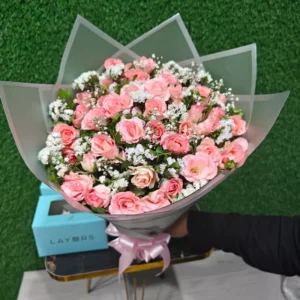 Full bouquet of light pink spray roses and white fillers wrapped in clear/white paper