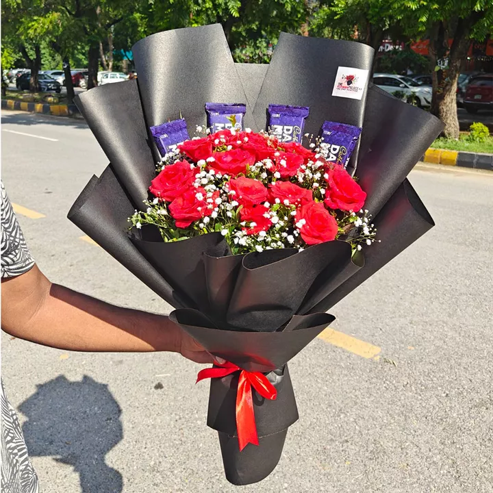 Red roses and baby's breath bouquet accented with Dairy Milk chocolate bars in black paper