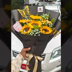 Yellow sunflowers bouquet with white baby's breath, dark wrapping, and gold butterfly accents