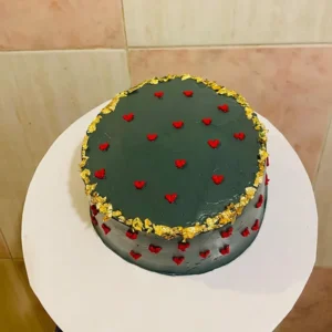 Deep black heart-shaped birthday cake with gold leaf trim and red hearts