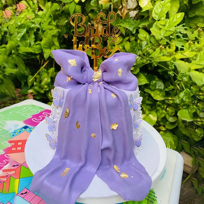 Lavender bridal shower cake with oversized purple ribbon bow and gold butterflies